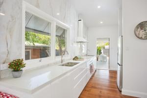 a white kitchen with a sink and a window at The Queenslander! Complete Entertainer - Huge - Stylish - Games - Full Level Pool Room - Smokehouse - Secure Parking - Yard #NEW! in Gold Coast