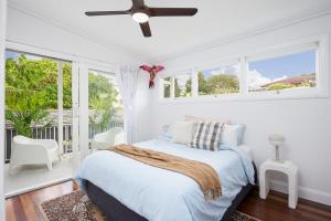 a white bedroom with a bed and windows at The Queenslander! Complete Entertainer - Huge - Stylish - Games - Full Level Pool Room - Smokehouse - Secure Parking - Yard #NEW! in Gold Coast