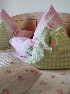 a bed with pink and green pillows on it at Eckarthof in Schneizlreuth