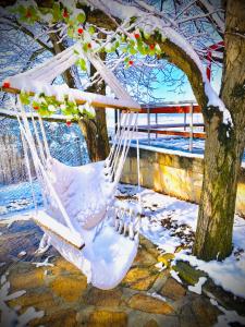 a white swing hanging from a tree in the snow at Хижа Манастирчето-Книжовник in Haskovo