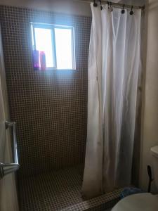 a bathroom with a shower with a white shower curtain at Airport Hostel in Ciudad Juárez