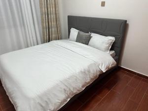a bed with white sheets and pillows in a bedroom at Home Croft Nairobi in Nairobi