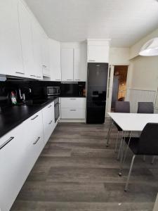 una cocina con armarios blancos y una mesa con sillas. en Anttoninvahe 7 130m2 with garden and sauna etc, en Rauma