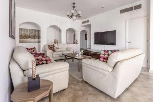 a living room with two white couches and a tv at Frank Porter - Al Badia 2 in Dubai