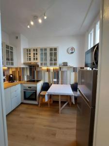 a kitchen with a table and a table and a refrigerator at Le Mirabeau Vue Lac in Évian-les-Bains