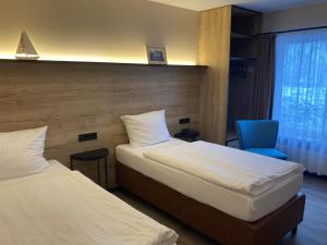 een hotelkamer met twee bedden en een blauwe stoel bij Oste-Hotel Superior in Bremervörde +29 foto's