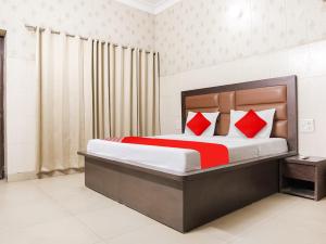 um quarto com uma cama grande e almofadas vermelhas em Super OYO Flagship Behl Ashiana em Amritsar