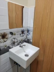ein Badezimmer mit einem weißen Waschbecken und einem Spiegel in der Unterkunft Roomstay Villa Tok Wan in Kuantan