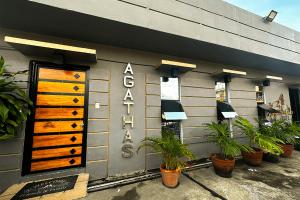 a store front with two wooden doors and potted plants at Agathas Hotel powered by Cocotel in Quezon