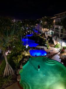 a man playing golf in a pool at night at Resort Queen Studio at Alex Beach Resort in Alexandra Headland