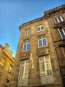 een hoog bakstenen gebouw met veel ramen erop bij Appartement XVIIIème centre historique in Bordeaux