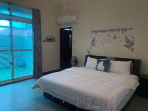 una camera da letto con un letto e una grande finestra di Ke Lai Inn B&B a Guanshan