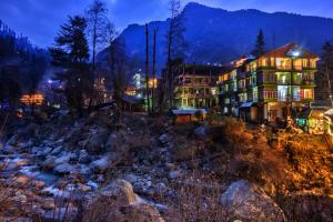 a hotel at night next to a river at HOTEL DREAM RIVER BY ARH HOTELS in Manāli