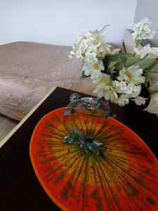 une plaque orange avec un vase de fleurs sur une table dans l'établissement Дво і одно кімнатні апартаменти новобуд рн авторинку трц Адреналін сіті, à Loutsk