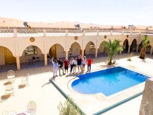 a group of people standing next to a swimming pool at Riad Akabar Merzouga in Merzouga