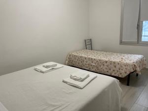 una camera con due letti con lenzuola e asciugamani bianchi di Apartment Orio Volta a Orio al Serio