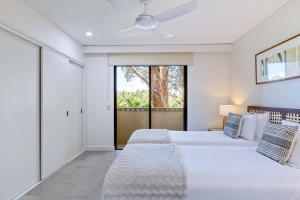 a bedroom with two beds and a ceiling fan at Bellflower at Temple - Family Beachside Paradise in Palm Cove