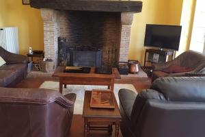 ein Wohnzimmer mit Ledermöbeln und Kamin in der Unterkunft Grande maison quercynoise avec piscine in Figeac