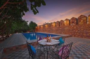 a patio with a table and chairs next to a pool at Aranya Vilas, Ranthambhore in Khilchipur