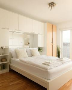 a white bedroom with a large bed with white cabinets at Modern Vienna Apartment in Prime Location in Vienna