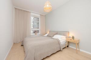 een witte slaapkamer met een bed en een raam bij Praga Arte Apartments with Parking & Balcony by Renters in Warschau