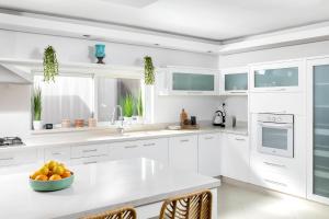 a white kitchen with a bowl of fruit on a counter at By Eezy- דירה משפחתית מפנקת 3 חדרי שינה - Hanechoshet in Eilat