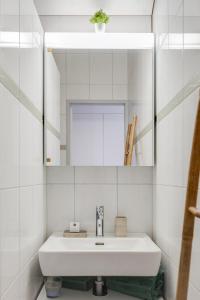 a white bathroom with a sink and a mirror at Bijou du Lac - mit Pool und Privatstrand in Därligen