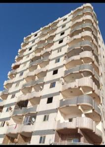 wysoki biały apartamentowiec z balkonem w obiekcie Family Condo With Panoramic Sea View 1 w Aleksandrii