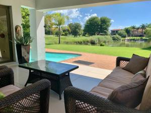 une terrasse avec une table, des chaises et une piscine dans l'établissement Westlake Waterfront Villa - Entire Villa, à Hartbeespoort