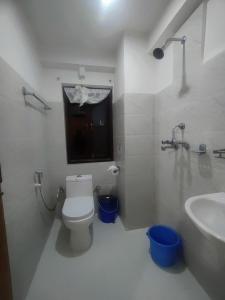 a white bathroom with a toilet and a sink at Bandipur Kaushi Inn in Bandīpur