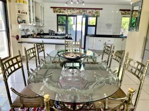 y cocina con mesa de cristal y sillas. en Westlake Waterfront Villa - Entire Villa, en Hartbeespoort