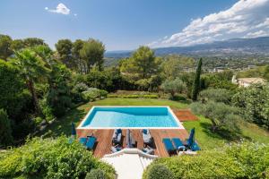 un'immagine di una piscina in un giardino con sedie blu e piscina di Villa Athéna - Villa dexception vue montagne a Mougins