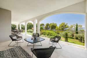 un patio interno con tavolo, sedie e ampia finestra di Villa Athéna - Villa dexception vue montagne a Mougins