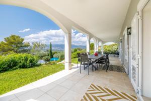 un patio esterno con tavolo, sedie e vista di Villa Athéna - Villa dexception vue montagne a Mougins