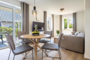 un soggiorno con tavolo, sedie e divano di Villa Dornkamp 2 - Luxuriöse Ferienwohnung für 4 Personen inklusive Garten und Sauna a Timmendorfer Strand