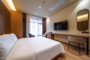 Cette chambre comprend un grand lit et une télévision. dans l'établissement Uiwang Milos Hotel, à Uiwang