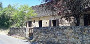 an old stone building next to a stone wall at Le fournil de la Blogeonie in Saint-Geniès