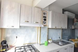 a kitchen with white cabinets and a sink and a stove at Mall LuxuryApartment Six in Bacău