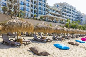 a group of chairs and straw umbrellas on a beach at Onyx 2 private beach apartment in Sveti Vlas