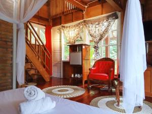 a bedroom with a bed and a red chair at Air Manis Hillside Villa Cafe & Resto in Padang