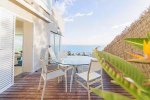 シッチェスにあるSitges Suites Bのガラスのテーブルと椅子、海を望むバルコニー