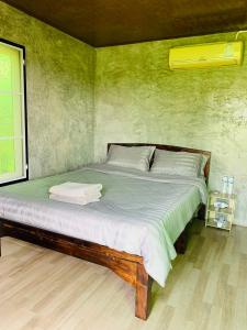 łóżko w pokoju z zieloną ścianą w obiekcie KraThom Doi Luang w mieście Chiang Dao