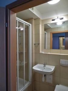 bagno con lavandino, doccia e specchio di Hotel Krakowiak a Cracovia