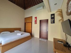 a bedroom with a bed and a flat screen tv at The Bagus in Kerobokan