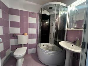 a purple and white bathroom with a toilet and a sink at Motel Gela in Inoc