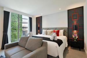 a bedroom with a large bed and a couch at Villa De Pranakorn in Bangkok