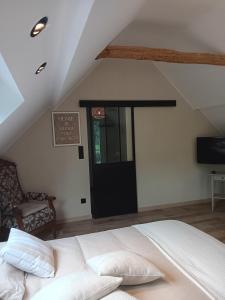 1 dormitorio con cama blanca y puerta negra en La chambre des daines en Binche