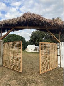 two wooden doors with a thatched roof in a field at Dome tent in Elyu will Pool Access for 10 pax 