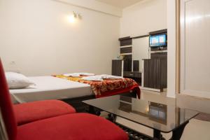 a bedroom with a bed and a table and a tv at Hotel Nilkantha in Mandarmoni