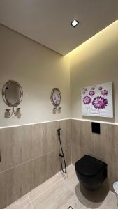 a bathroom with a toilet and two pictures on the wall at شقه مترفه النخيل ٣ in Riyadh